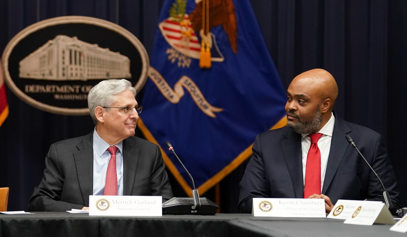 U.S. Attorney General Merrick Garland looks toward federal prosecutor Kevin Chambers (R) after Chambers was appointed to be the Justice Department's chief pandemic fraud prosecutor, during a meeting of the coronavirus disease (COVID-19) Fraud Enforcement Task Force at the Justice Department on March 10, 2022.